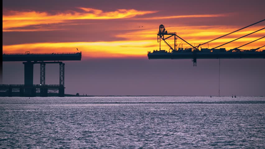 Dramatic colorful twilight over the nearly finished Tamkang Bridge construction in Tamsui New Taipei Taiwan. Red orange and pink dreamlike sky.