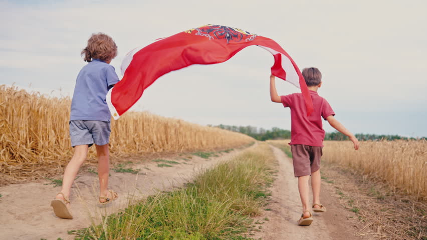 Children running with Austrian flag through golden wheat field under summer sky