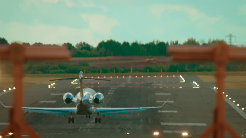 Private business jet landing on runway during clear weather. Luxury aircraft touching down on landing strip with smoke rising from wheels under bright sky. Corporate jet arriving on airfield in sunny
