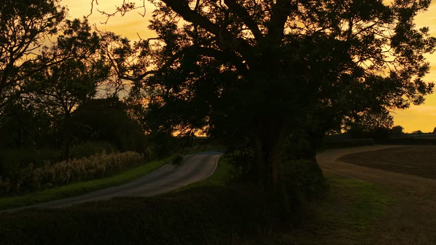 Car moving on countryside road during sunset. Traveling car, road trip adventure, enjoying countryside landscape. Vehicle driving on rural roadway at sundown