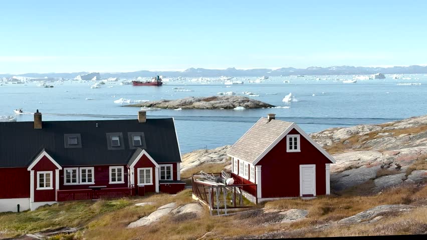 Colorful houses dot the hillside of a small town in Greenland during a cloudy afternoon