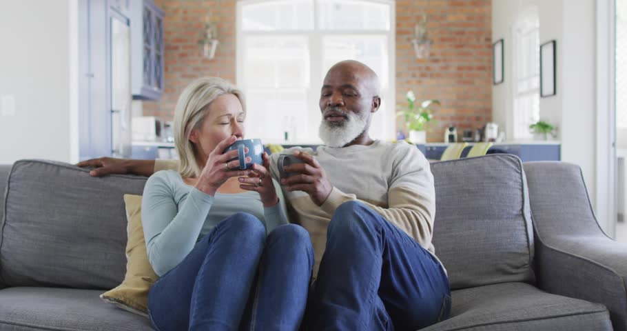 Mature woman and man lowering mugs spawning waveforms and code overlay visualizing technology data. Romantic, cozy, contemporary, digital, intimacy, communication, relaxation