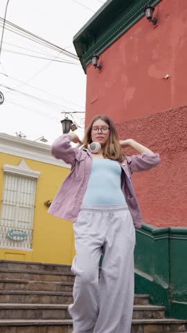 Stylish young woman performing energetic hip hop moves on urban stairs. Female dancer expressing herself with rhythm and grace in slow motion