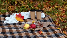Cozy autumn picnic with coffee cups, apples and pastries on blanket while yellow leaves fall gently - Powered by Shutterstock - Get 15% off with code: PIKWIZARD15