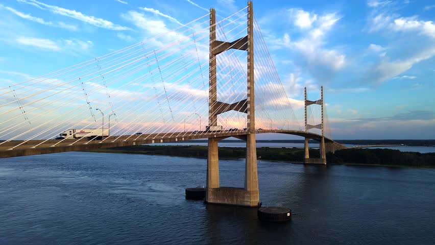 Golden light illuminates the Dames Point Bridge. Sunset reflections enhance the Florida skyline.
