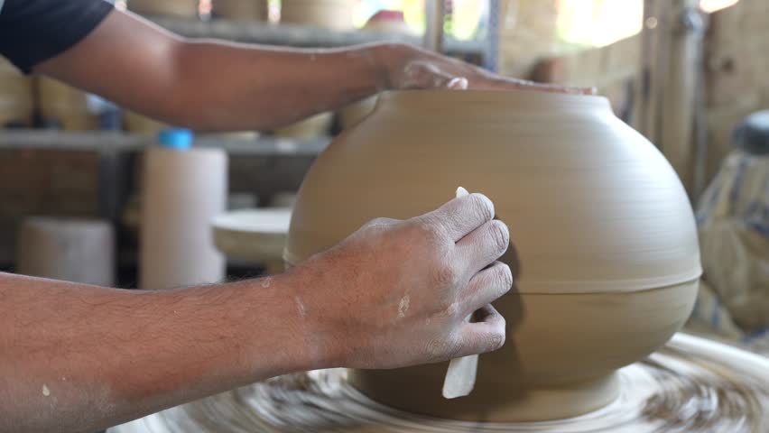 Pottery in progress. Craftsman polishes the clay pot he just made