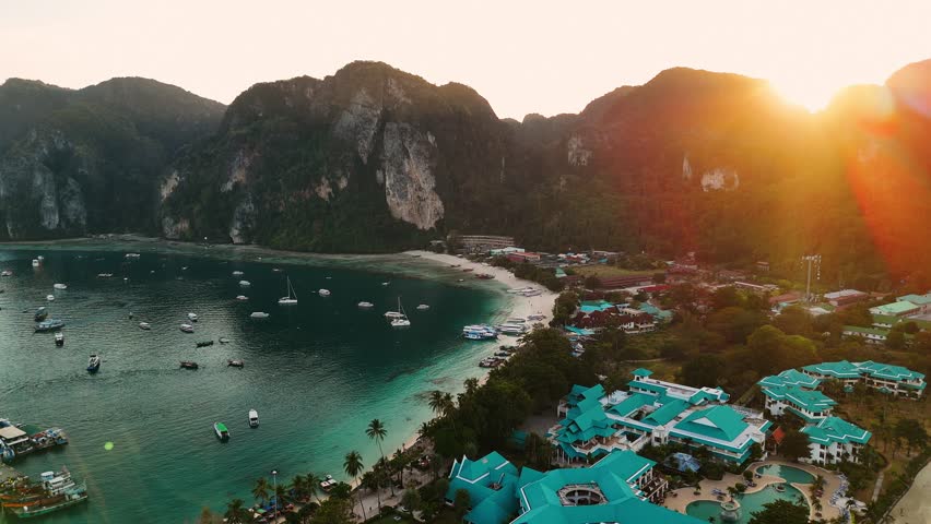 Aerial view of golden sunset tonsai village at phi phi island picturesque coastline with turquoise waters and mountain, Thailand