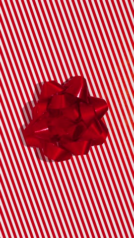 Unwrapping gift revealing a green screen - Stop Motion Animation - Red bow on Christmas wrapping paper. Vertical Screen Orientation Video