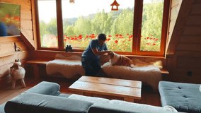 Man enjoys playful moments with corgi in cozy cabin with scenic views at sunset - Powered by Shutterstock - Get 15% off with code: PIKWIZARD15