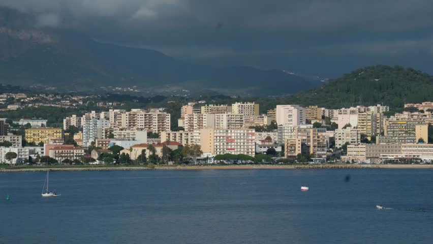 Scenic coastline of Corsica island seen from cruise ship with green hills rocky cliffs turquoise sea and coastal towns in sunlight Mediterranean travel destination natural landscape and summer view