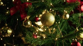 Warm and sparkling close up of a festive Christmas tree adorned with shiny gold and red baubles, illuminated by glowing string lights - Powered by Shutterstock - Get 15% off with code: PIKWIZARD15