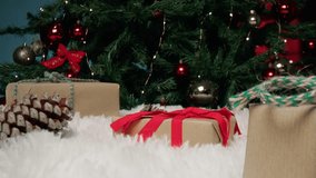 A hand retrieves a small, red ribboned gift from a cozy white display, revealing a Merry Christmas sign in front of a beautifully decorated tree - Powered by Shutterstock - Get 15% off with code: PIKWIZARD15