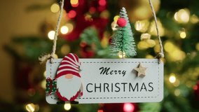 Festive Merry Christmas wooden sign, adorned with a gnome and a small tree, hangs against a beautifully blurred background of twinkling holiday lights on a Christmas tree - Powered by Shutterstock - Get 15% off with code: PIKWIZARD15