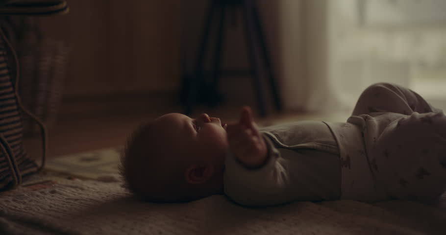 Close-up view of an infant lying on a blanket with a thoughtful, dreamy expression, capturing a moment of nostalgia and contemplation.