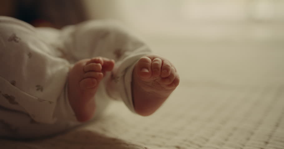Close-up of a tiny baby boy playing with his velvety feet, emphasizing parenthood.
