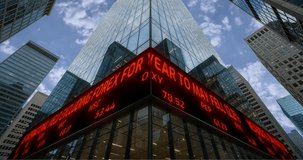 A low-angle shot of a modern, glass-fronted skyscraper displaying red LED stock market ticker news and data in a bustling financial district. - Powered by Shutterstock - Get 15% off with code: PIKWIZARD15