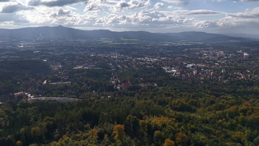 Breathtaking aerial view showcasing a picturesque town surrounded by vibrant greenery and dramatic cloudscapes.