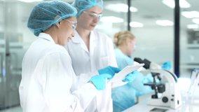 A diverse team of female scientists collaborates in a modern research lab. Two colleagues review experimental data on a digital tablet while another works at a microscope. - Powered by Shutterstock - Get 15% off with code: PIKWIZARD15