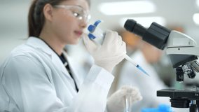A dedicated female scientist in a lab coat and safety goggles looks intently through a microscope, conducting detailed research and analyzing a specimen in a bright, modern laboratory. - Powered by Shutterstock - Get 15% off with code: PIKWIZARD15