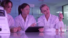 A diverse and happy team of young female scientists collaborates in a futuristic lab, discussing innovative ideas and reviewing research data together on a digital tablet. - Powered by Shutterstock - Get 15% off with code: PIKWIZARD15
