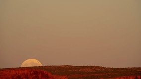 Timelapse of a large full moon rising over desert terrain as the sun is setting - Powered by Shutterstock - Get 15% off with code: PIKWIZARD15