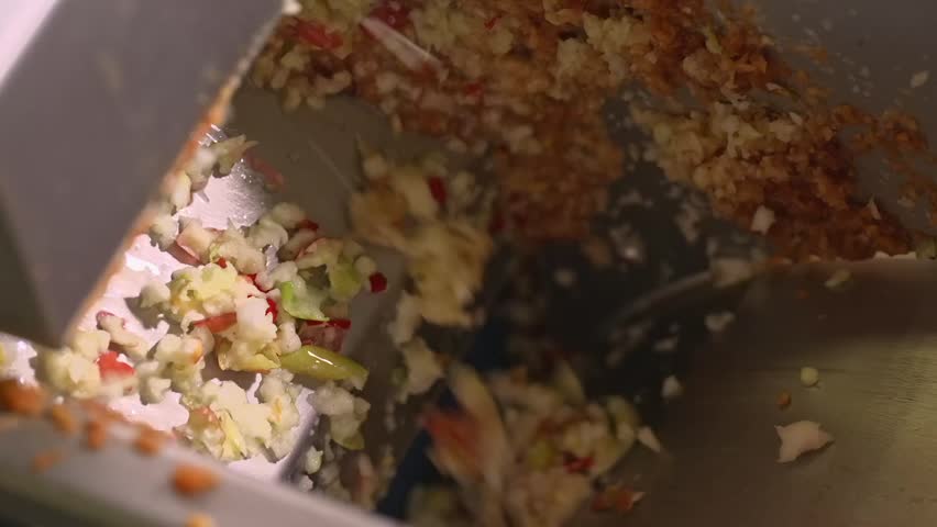Chopped apples and fruit pieces inside an industrial crusher during juice production. The raw mix is processed before pressing in a modern food manufacturing facility.