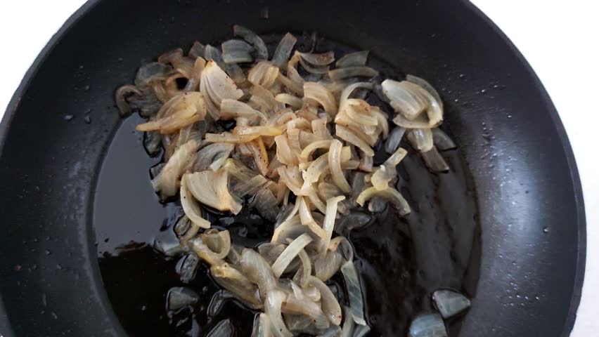 Sizzling onions and garlic hit hot oil-edges browning, aroma intensifying. A macro view of early saute stage, rich in texture and flavor-building action