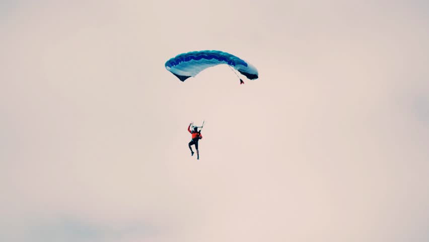 A parachute descending smoothly before landing on open terrain. The scene captures the thrill of skydiving and aerial adventure, perfect for themes related to aviation, air sports, rescue training