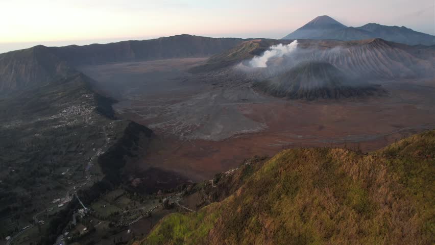 Drone view of Mount Bromo, Batok, and Semeru volcanoes over the Sea of Sand in East Java, Indonesia. Majestic sunrise sunset travel and nature footage.
