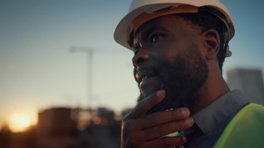 Thoughtful engineer developing new building, make decision at construction site. Portrait of professional architect and developer examining new building, controlling process and looking at computer