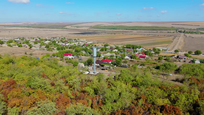 Aerial view of a water tower surrounded by vibrant autumn foliage and rural landscape, showcasing the transition of seasons and the harmony of nature and infrastructure