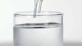 Pipettes release colored drops into clear water, creating swirling diffusion patterns under bright studio lighting - Powered by Shutterstock - Get 15% off with code: PIKWIZARD15