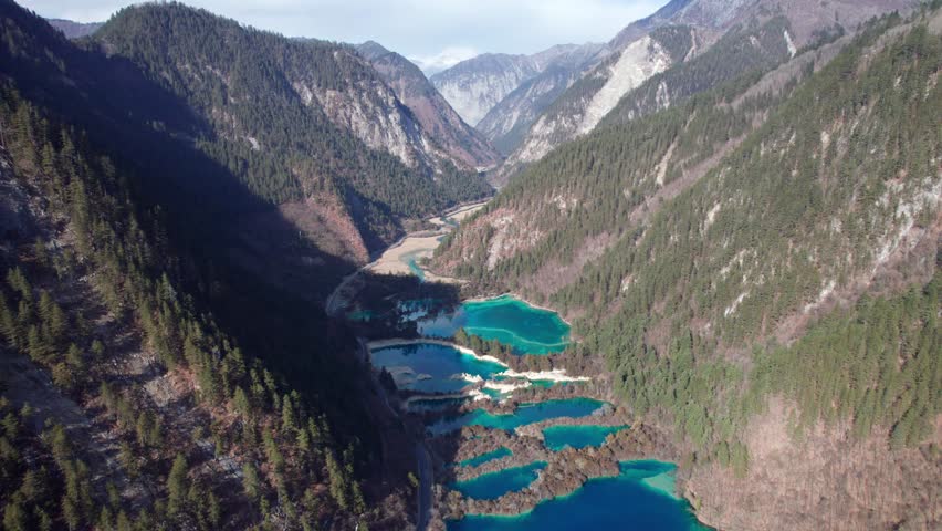 Drone view of Jiuzhaigou National Park in spring in Sichuan Province China. It features cascading waterfalls, turquoise blue lakes, and stunning mountain valleys. 4K real time footage travel concept