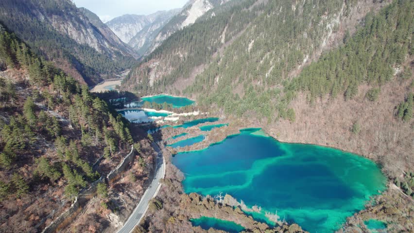 Drone view of Jiuzhaigou National Park in spring in Sichuan Province China. It features cascading waterfalls, turquoise blue lakes, and stunning mountain valleys. 4K real time footage travel concept