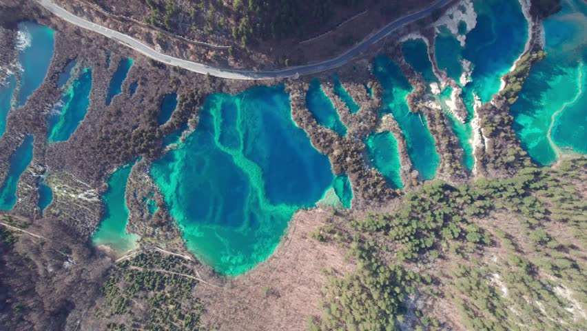 Drone view of Jiuzhaigou National Park in spring in Sichuan Province China. It features cascading waterfalls, turquoise blue lakes, and stunning mountain valleys. 4K real time footage travel concept