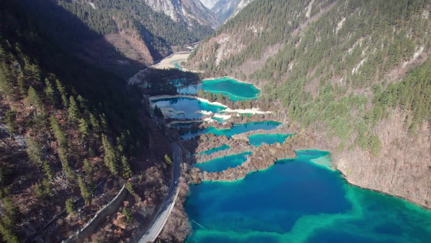 Drone view of Jiuzhaigou National Park in spring in Sichuan Province China. It features cascading waterfalls, turquoise blue lakes, and stunning mountain valleys. 4K real time footage travel concept