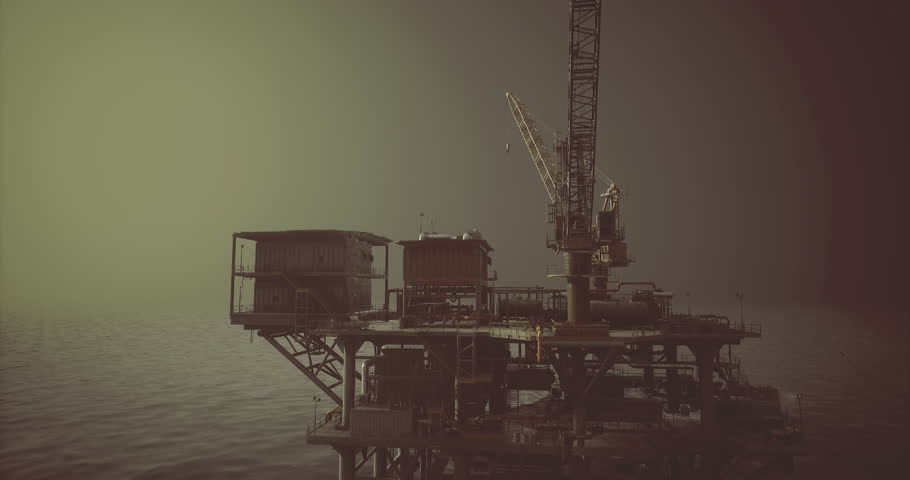 An offshore oil drilling platform towers above the tranquil sea, silhouetted against a dim sky. Equipment and structures indicate active drilling operations in a remote location.
