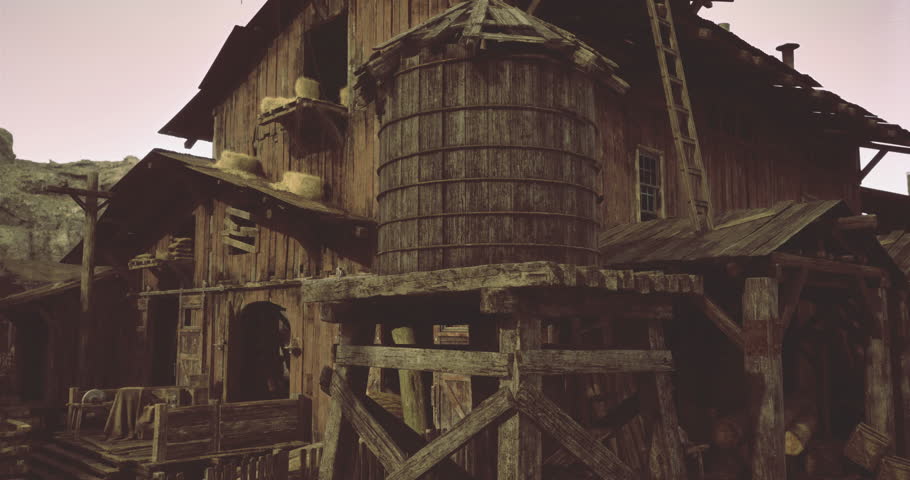 A rustic barn stands with a large wooden water tower nearby, surrounded by a quiet rural landscape. The sun sets, casting a warm glow over the weathered structures.