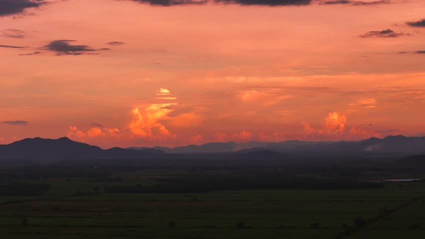 Aerial view of glowing orange sunset over mountain valley and colorful sky