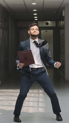 Confident entrepreneur celebrating success in office corridor dancing slow motion vertical video concept of positive energy inner strength and motivation