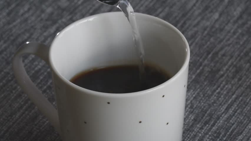 Watching hot water being poured over coffee grounds in a cozy setting enhances the morning routine.
