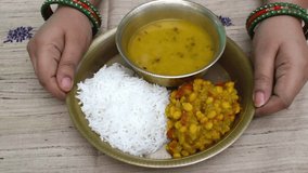 lady serving Chhath Puja Nahay Khaye thali or plate with steamed rice (chawal), dal, and lauki ki sabji (bottle gourd curry) to devotees.  - Powered by Shutterstock - Get 15% off with code: PIKWIZARD15
