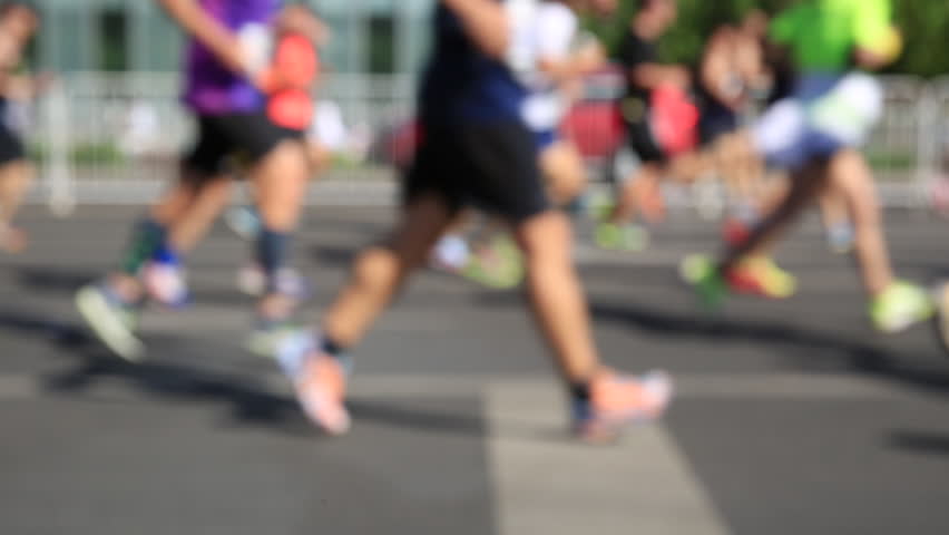 Defocused marathon runners running on city road