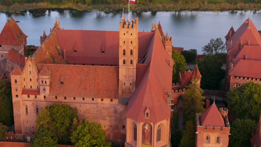 Castle of the Teutonic Order in Malbork by the Nogat river at sunset. Poland