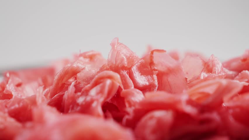 Pickled red ginger for sushi and rolls. Ginger for Asian cuisine. Close-up of hand takes up ginger with wooden sticks. High quality 4k footage