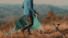 Traveler struggles to set up camp near a tent during strong wind in the mountains. Outdoor adventure scene shows resilience, survival skills, and the challenges of wild camping in harsh conditions. - Powered by Shutterstock - Get 15% off with code: PIKWIZARD15