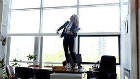 Dancing on her desk woman demonstrates pure elation celebrating business achievements. Female jubilant dance in office setting professional victories excitement and energy personal satisfaction. - Powered by Shutterstock - Get 15% off with code: PIKWIZARD15