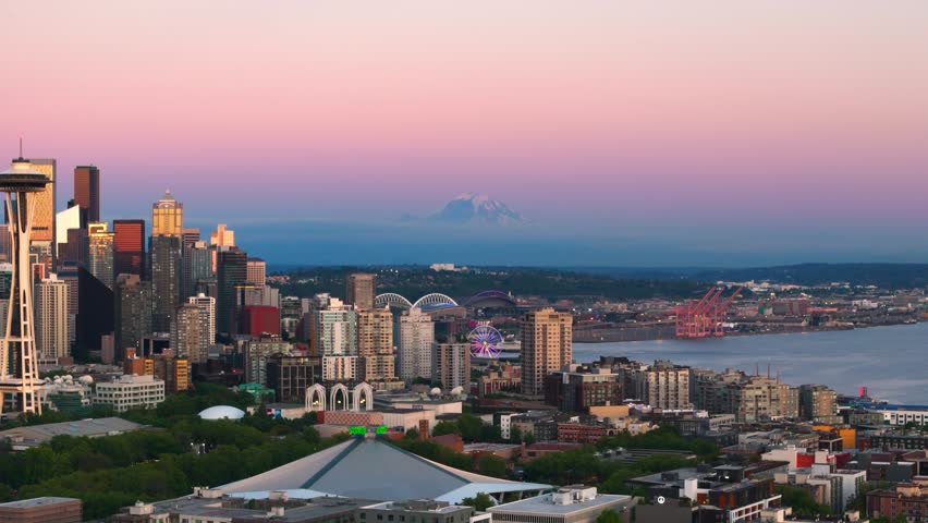 Drone shot of Mount Rainier looming in the sunset filled distance behind Seattle