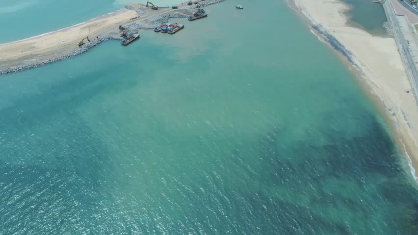 A view of the colombo port city under construction,
Aerial view, Cranes and construction machinery, The 
drone is moving slowly, Breakwater walls, Ship, 
drilling, reflection, moment, sunset.