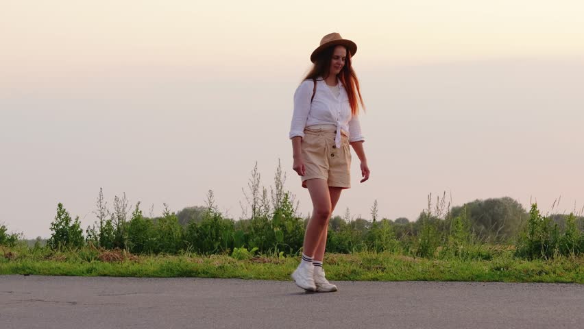 Woman dressed casually walks along a peaceful path at sunset, surrounded by greenery and soft light